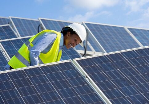 Electrical engineer woman checking solar photovoltaic panels on the roof of a solar farm.